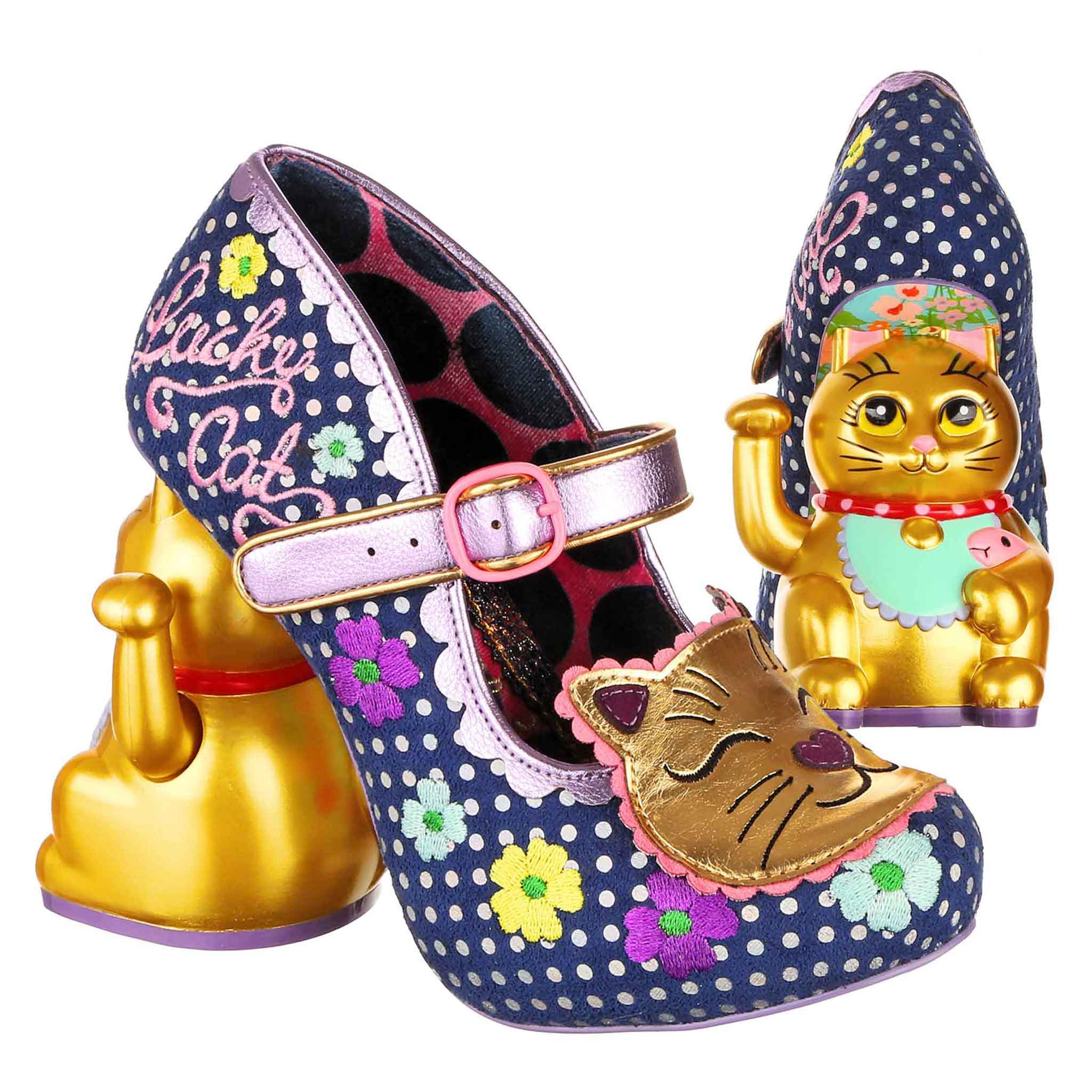 Navy blue and white polka dot high-heeled shoes with a purple Mary-Jane strap and pink buckle fastening with floral details and Lucky Cat embroidered on the side and a gold cat face applique on the toe, with gold waving cat concept heels on a white background.