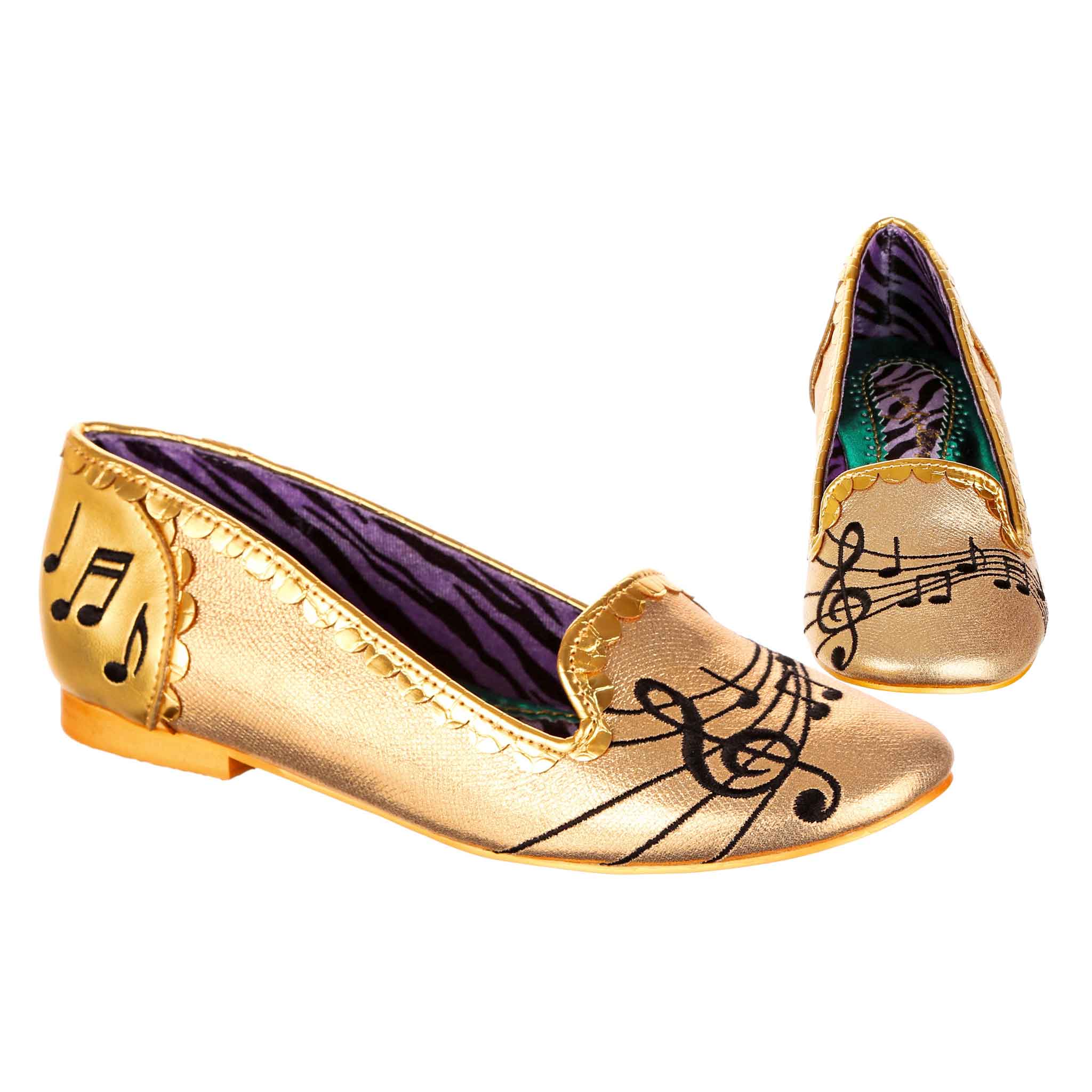 Gold slip on ballet pump shoes with music note designs in black embroiderey on a white background
