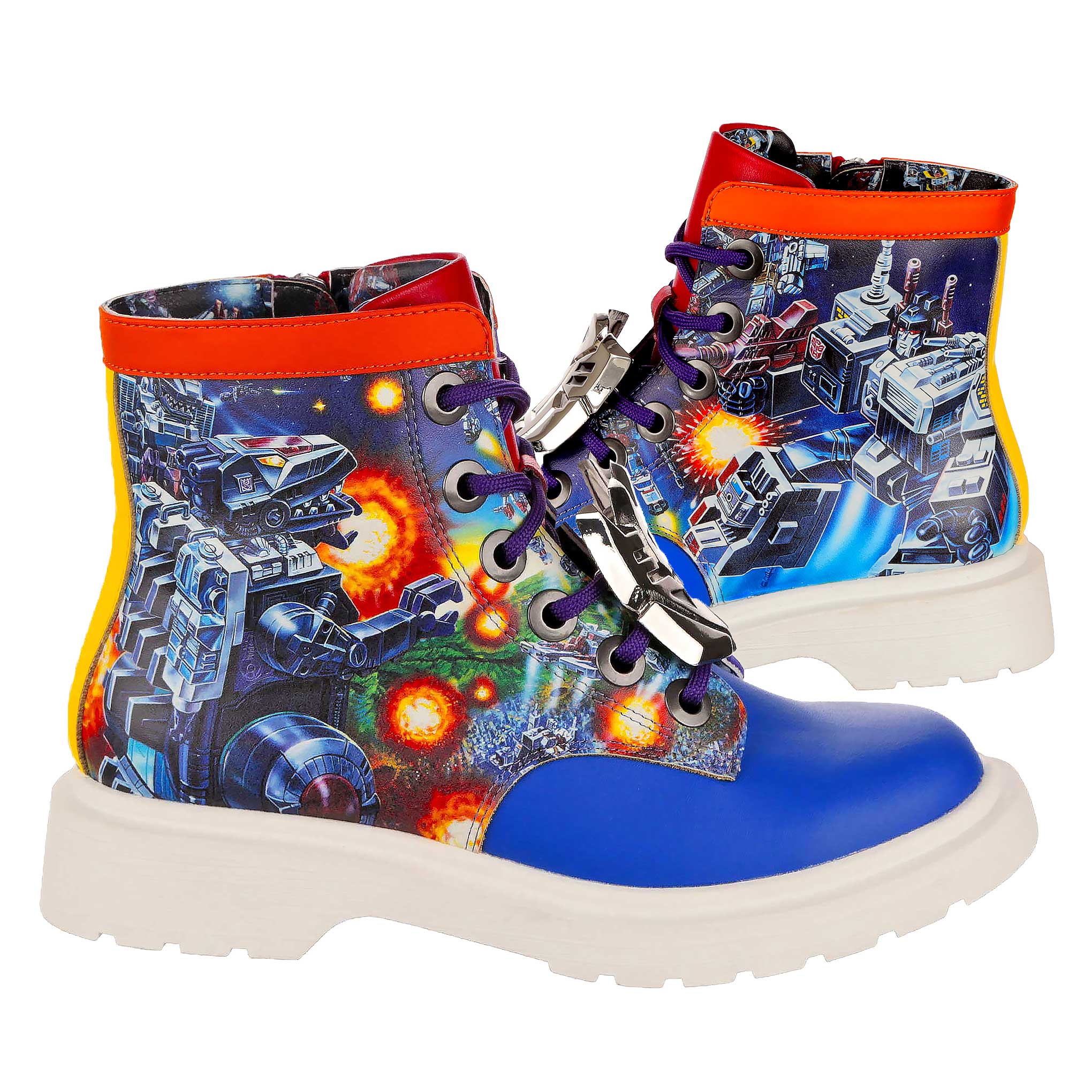 A pair of lace-up ankle boots with a vintage Transformers scene showing Trypticon battling Metroplex on either side of the boot. A cobalt blue toe contrasts with the blue, orange and green Transformers print on the main body of the shoe. An orange edging runs along the top of the boot whilst a white chunky sole finishes the lace-up boots. Purple laces thread through the boot with silver metallic lace charms sitting on the laces. 