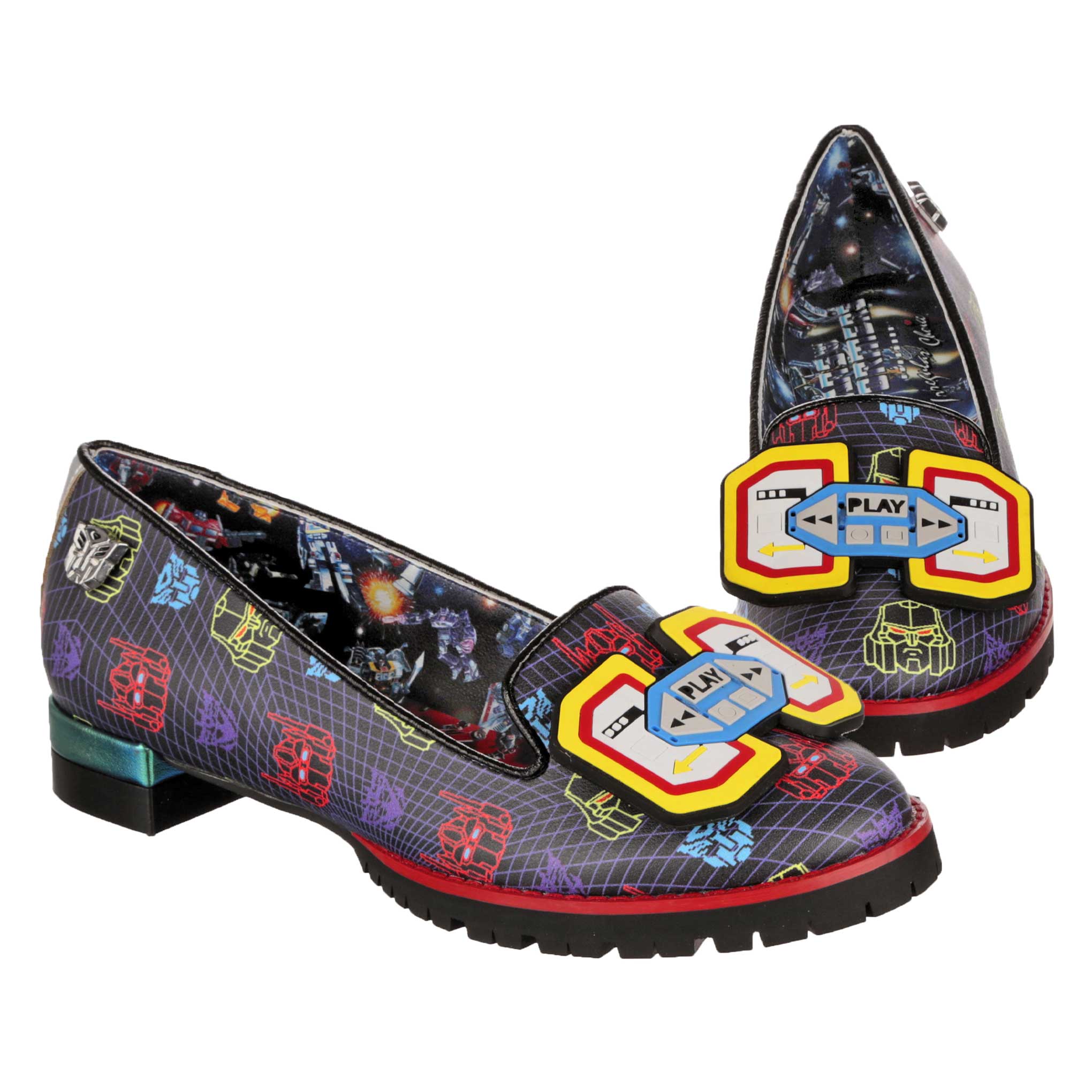 A pair of Synthwave Transformers themed black ballet pumps featuring a retro pixal art print with Autobot and Soundwave logos on. A Transformers print lines the inside of the shoe showing Transformers battling in space. A rubber Play and stop cassette player decal sits on the toe of the shoe whilst black chunky soles finish off these slip-on flats. 