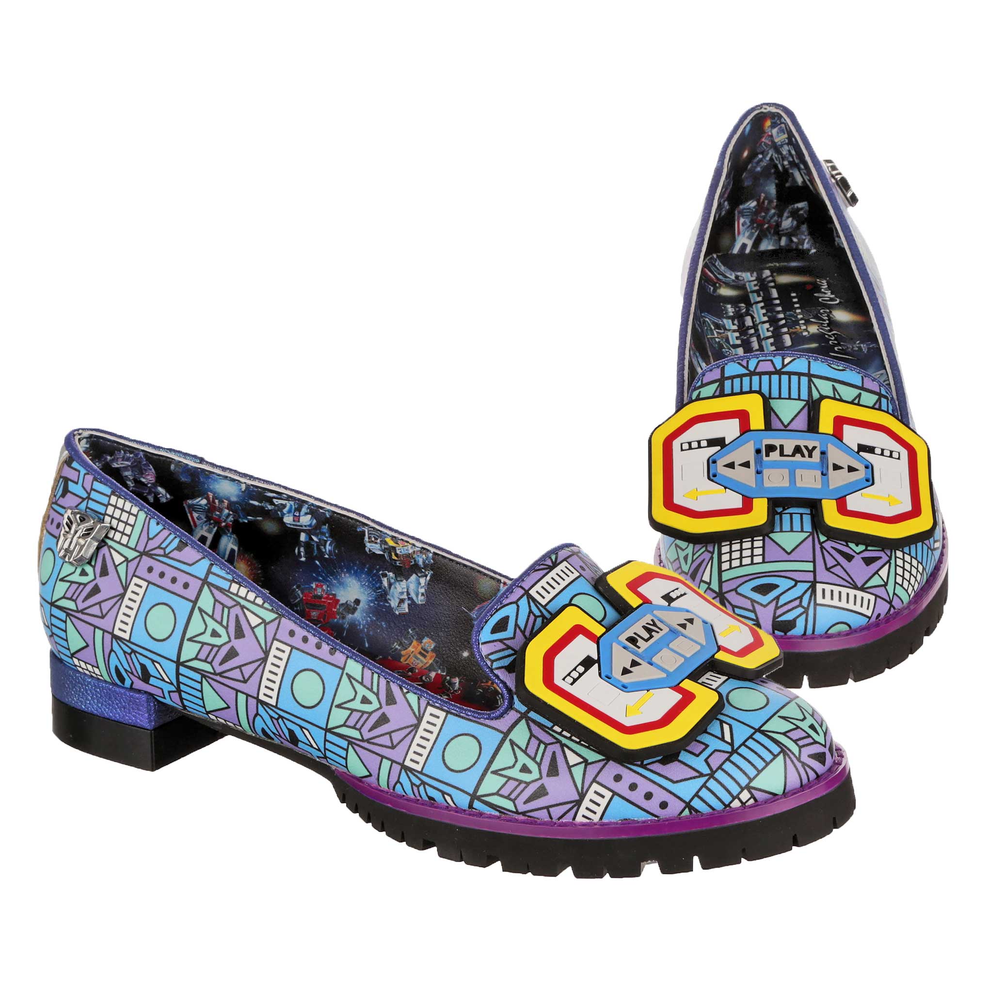 A pair of Synthwave Transformers themed blue ballet pumps featuring a retro pixal art print with Autobot and Soundwave logos on. A Transformers print lines the inside of the shoe showing Transformers battling in space. A rubber Play and stop cassette player decal sits on the toe of the shoe whilst black chunky soles finish off these slip-on flats. 