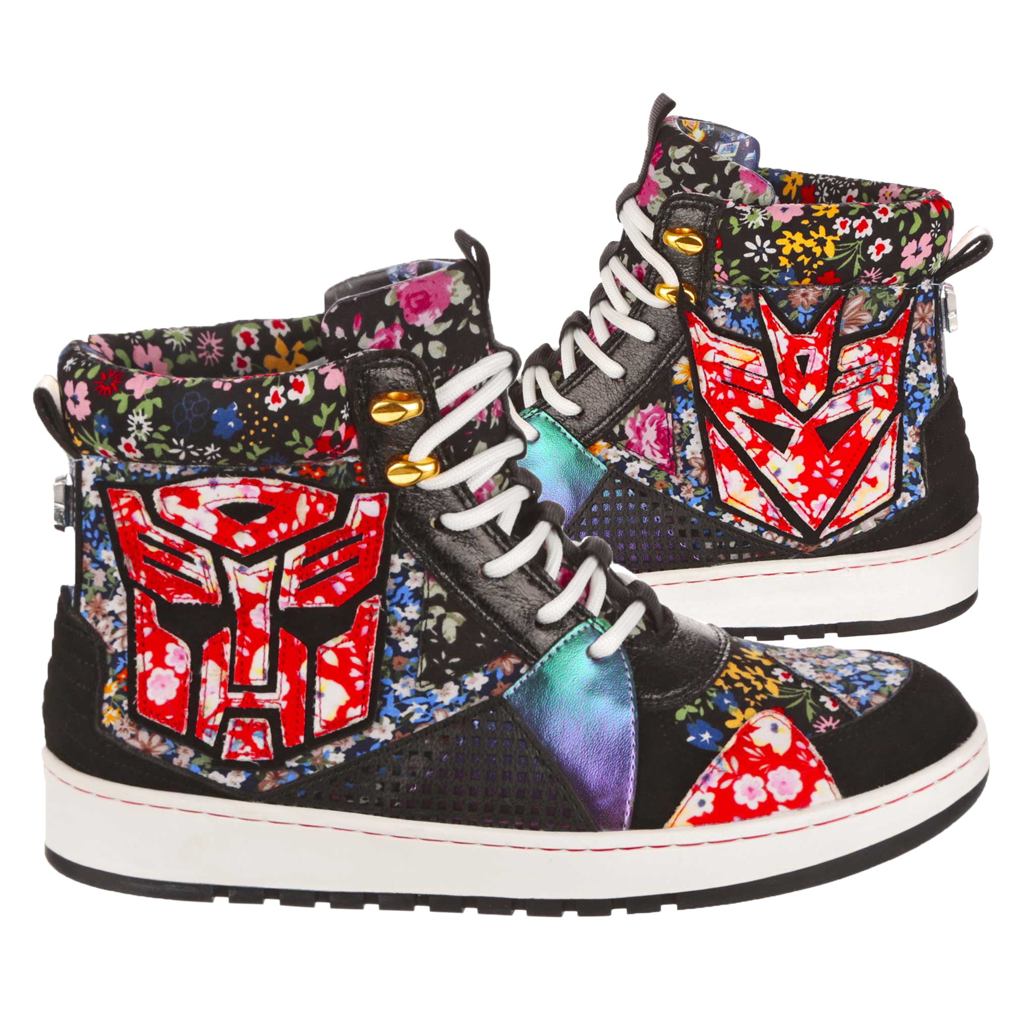 A pair of lace-up Transformers inspired high top trainers sit side by side. Multicoloured retro floral prints are mixed with red and black details as well as a red floral embroidered Decepticon and Autobot logo on each boot. A white and black chunky sole matches the white laces while a black pull up tab sits at the back of these flat trainer boots.